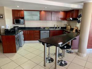 eine Küche mit Holzschränken und einer schwarzen Arbeitsplatte in der Unterkunft Spacious 2 bedroom space with breathtaking seaview in Mossel Bay
