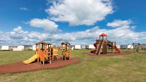 a group of playground equipment in a field at Holiday park caravan Fluffy in Harts Holiday Park in Leysdown-on-Sea