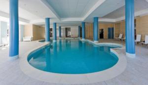 - une grande piscine avec colonnes bleues dans un bâtiment dans l'établissement La foux d allos Superbe appartement 6 couchages ,piscine, à Allos