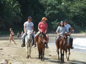 un grupo de personas montando a caballo en la playa en Hotel Casitas Mar y Luz, en Puerto Viejo