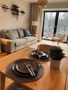 una sala de estar con una mesa con platos y copas de vino en Albatross Beach Apartment - SPA, Sea and Forest, en Ķesterciems