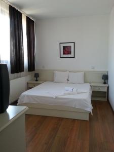 a bedroom with a white bed and two tables and a television at Banu Manta Apartments in Bucharest