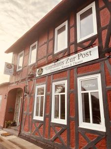 un viejo edificio de ladrillo con un cartel. en Gasthaus Zur Post en Uetze