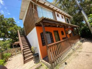 an orange and white house with a porch and stairs at Pousada Beija Flor in Ilha do Mel