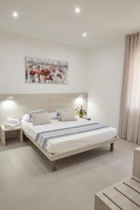 a white bedroom with a large bed and a painting on the wall at Kalsa Sicilian Rooms in Partinico