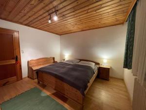 a bedroom with a wooden bed and a wooden ceiling at Haus Kreuzboden in Hundsdorf