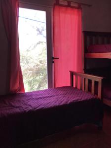 sypialnia z fioletowym łóżkiem i oknem w obiekcie El Descanso Housse II w mieście San Miguel de Tucumán