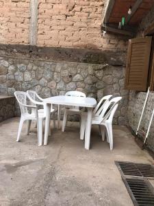 una mesa y sillas blancas frente a una pared de piedra en El Descanso Housse II en San Miguel de Tucumán