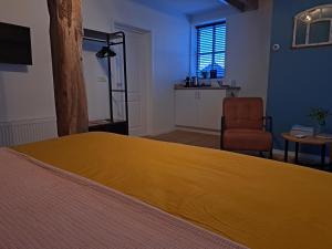 a bedroom with a large yellow bed and a chair at Hessener Esch in Dalfsen