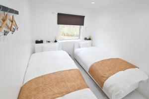 two beds in a white room with a window at NISEKO EPIC HOUSE in Niseko