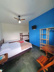 a bedroom with a bed and a blue wall at Pousada Retiro das Caravelas in Cananéia