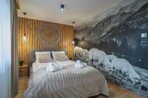 a bedroom with a bed with a large painting on the wall at Apartamenty Osada Antałówka Zakopane in Zakopane