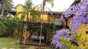 una casa con flores púrpuras delante de ella en Conchas do Mar Residence, en Itacaré