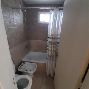 y baño con aseo, bañera y lavamanos. en Departamento Jacinto Ríos con pileta en Córdoba