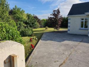 um quintal com uma casa e uma entrada em Peaceful Farm Cottage in Menlough near Mountbellew, Ballinasloe, Athlone & Galway em Galway