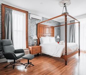 a bedroom with a canopy bed and a chair at Hotel de Paris Montreal in Montreal