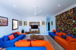 a living room with blue couches and orange pillows at ChezBabo in Ngaparou