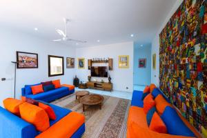 a living room with blue couches and orange pillows at ChezBabo Wellness Hotel in Ngaparou