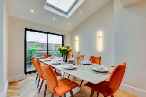 a dining room with a white table and orange chairs at Newly renovated 4 Bedroom Cottage with Wood Burner in Aysgarth