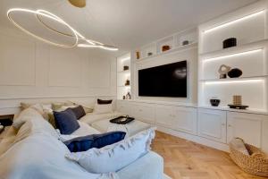 ein Wohnzimmer mit einem weißen Sofa und einem Fernseher in der Unterkunft Newly renovated 4 Bedroom Cottage with Wood Burner in Aysgarth