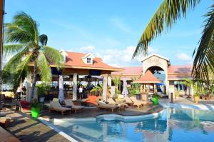 a resort with a swimming pool with chairs and palm trees at Sunset Beach Condo - Luxury 1BR Suite next to The Morgan Resort in Maho Reef