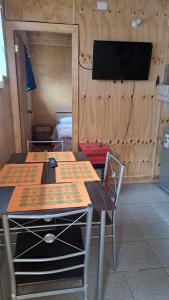 een tafel en een stoel in een kamer met een tv bij Cabaña Don Ricardo in Coihaique