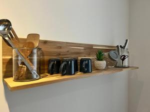 una estantería de madera con varios utensilios de cocina. en Le Rêve Bleu Appartement Hyper-centre en Carcasona