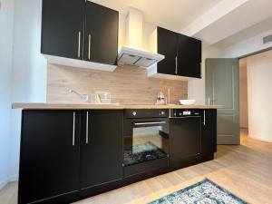 cocina con armarios negros y fogones en Le Rêve Bleu Appartement Hyper-centre en Carcassonne