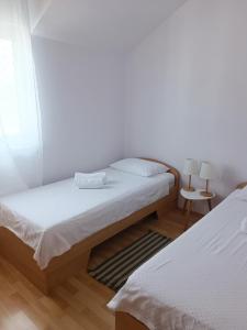 Habitación con 2 camas, paredes blancas y suelo de madera. en The Sea Nook, en Srima