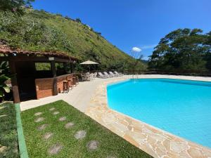 a large swimming pool with chairs and a building at Chalés da montanha in Itaipava