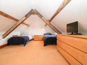a attic bedroom with two beds and a flat screen tv at Gladstone in Pwllheli
