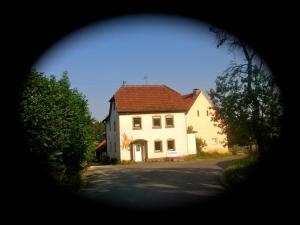una casa blanca con techo rojo en una calle en Kleine Ferienwohnung auf dem Land, Haus Hans Stepha, en Gössweinstein