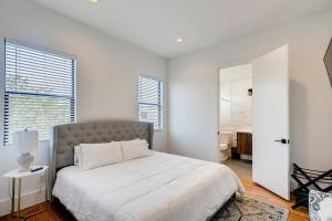 a white bedroom with a bed and a large window at 4 Story Home Mins To Downtown Houston with City Views in Houston