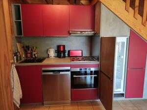 uma cozinha com armários vermelhos e um forno com placa de fogão em Chalet savoyard indépendant em La Toussuire