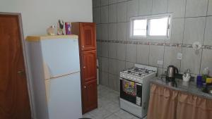 Il comprend une cuisine équipée d'un réfrigérateur blanc et d'une cuisinière. dans l'établissement El Depto de la Abuela, à Puerto Iguazú 4 autres photos