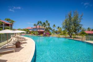 una piscina en un complejo con sillas y sombrillas en Villa Maorie 1 chambre avec piscine privée en Le François