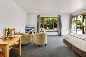 a bedroom with a bed and a desk and chairs at Harrogate Gardens Motel in Hanmer Springs