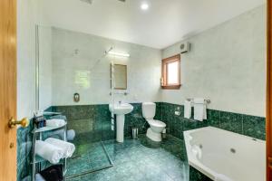 uma casa de banho com uma banheira, um WC e um lavatório. em Harrogate Gardens Motel em Hanmer Springs
