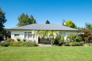 a white house with a green yard at Harrogate Gardens Motel in Hanmer Springs