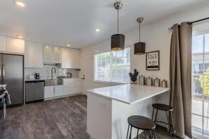 una cocina blanca con encimera y 2 taburetes en Marbella Lane - Neat and Cozy Modern Home, en East Palo Alto