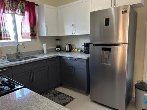 a kitchen with a stainless steel refrigerator and white cabinets at Seamist villa @Oceanpointe Lucea comfy 2BR w/pool gym & parking in Lucea