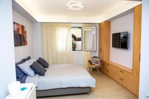 Studio apartment with all amenities in Kolonaki في أثينا: غرفة نوم صغيرة بها سرير وتلفزيون