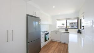 une cuisine avec des armoires blanches et un réfrigérateur en acier inoxydable dans l'établissement Talinga 4, à Yamba 7 autres photos