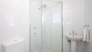 une salle de bain blanche avec une douche et un lavabo dans l'établissement Talinga 4, à Yamba