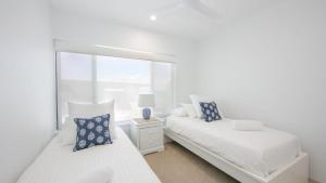 - une chambre blanche avec 2 lits et un miroir dans l'établissement Talinga 4, à Yamba