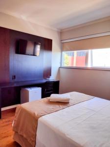 um quarto com uma cama branca e uma janela em Hotel Itália em Paranavaí