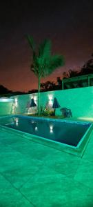 uma piscina à noite com uma palmeira e luzes em Quarto Suíte Itapoá - SC em Itapoá