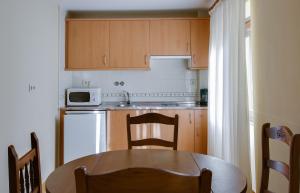 a small kitchen with a table and a microwave at Apartahotel Faure in Sallent de Gállego
