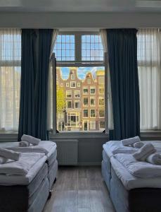 a bedroom with two beds and a large window at Facade Hotel Amsterdam in Amsterdam