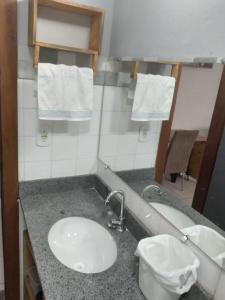 a bathroom with a sink and a mirror at Temporada Ilheus na Praia dos Milionarios Kitnet in Ilhéus